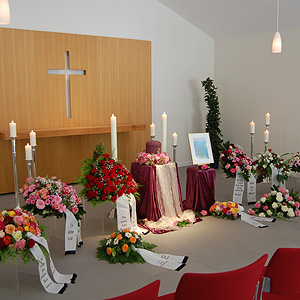 Trauerhalle des Friedhof Rellingen mit Kränzen, Kerzen, Urne