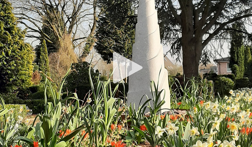 Friedhof mit Blumenbeet und Kunstwerk Himmelsleiter im Frühling, grün und bunt