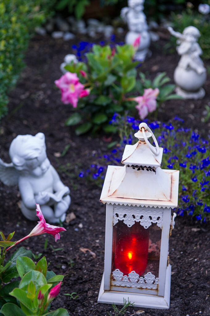 Grabgestaltung mit Grableuchte, Figuren und Bepflanzung mit Blumen in Blau, Rosa, Weiß