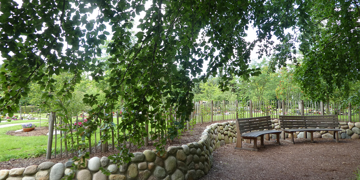 Friedhof Baumpark mit Bänken und Steinmauer