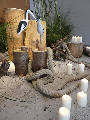 Trauerfeier: Kerzen, Baumstümpf, Störche, Tau und Sand