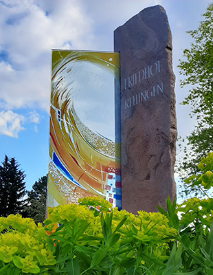 Friedhof Rellingen Kunstwerk vor grünen Pflanzen mit Bäumen vor Himmel